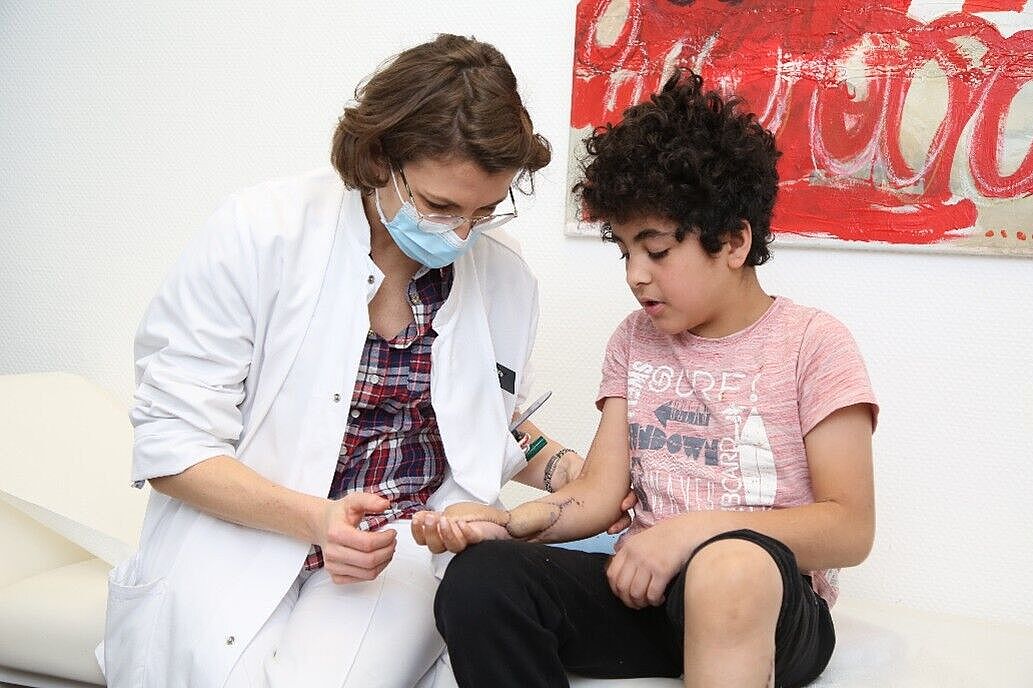 BG Klinik rettet Arm von kleinem Jungen Ärztin sieht sich den Unterarm des kleinen Jungen an