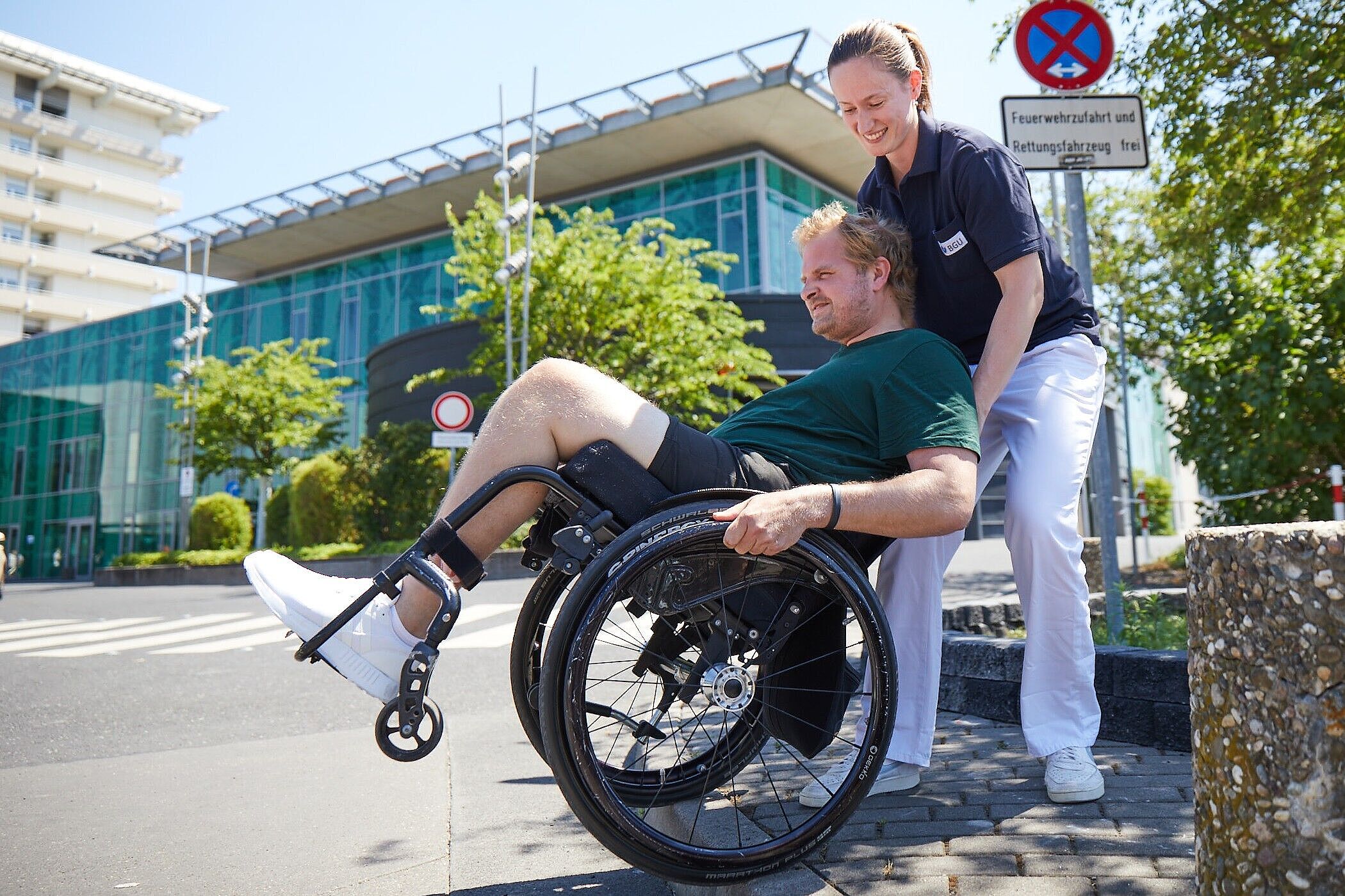 Therapeutin und Patient im Rollstuhl